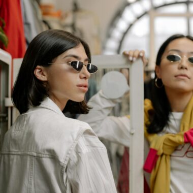 Two stylish women trying sunglasses in a chic boutique setting.