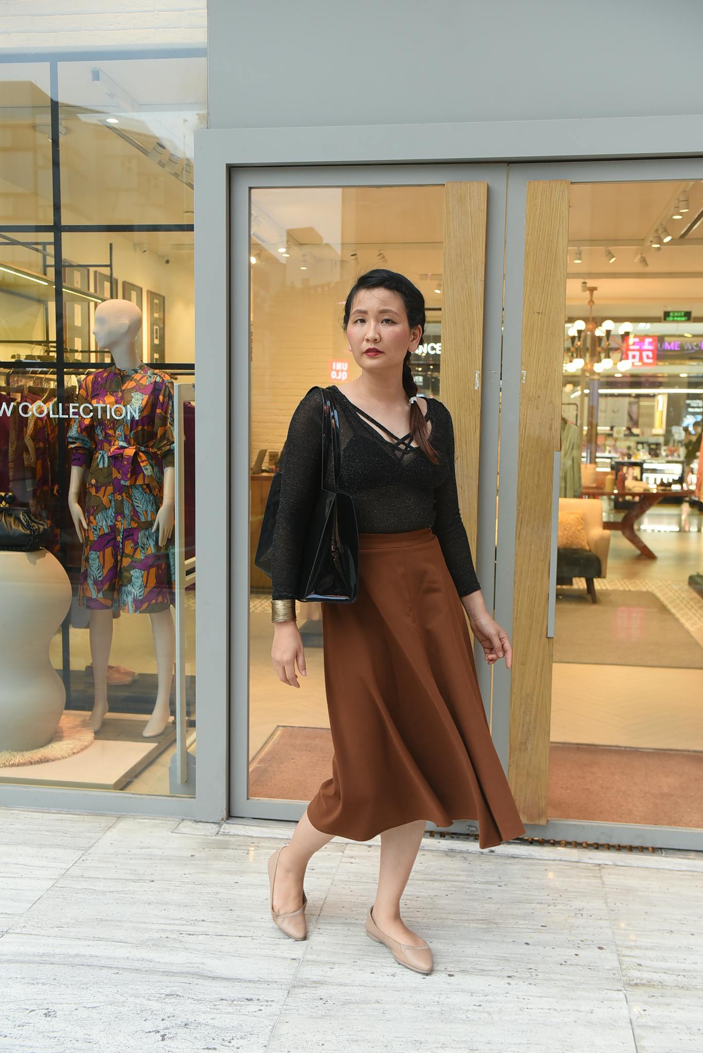 Woman in fashionable attire stands outside a boutique, blending elegance with a modern look.