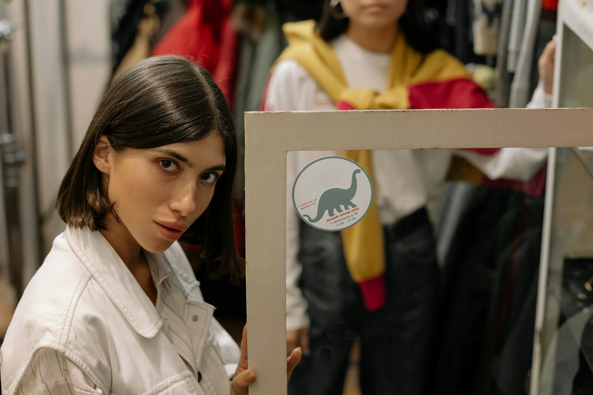 Young woman in a fashionable boutique posing confidently in front of a mirror.